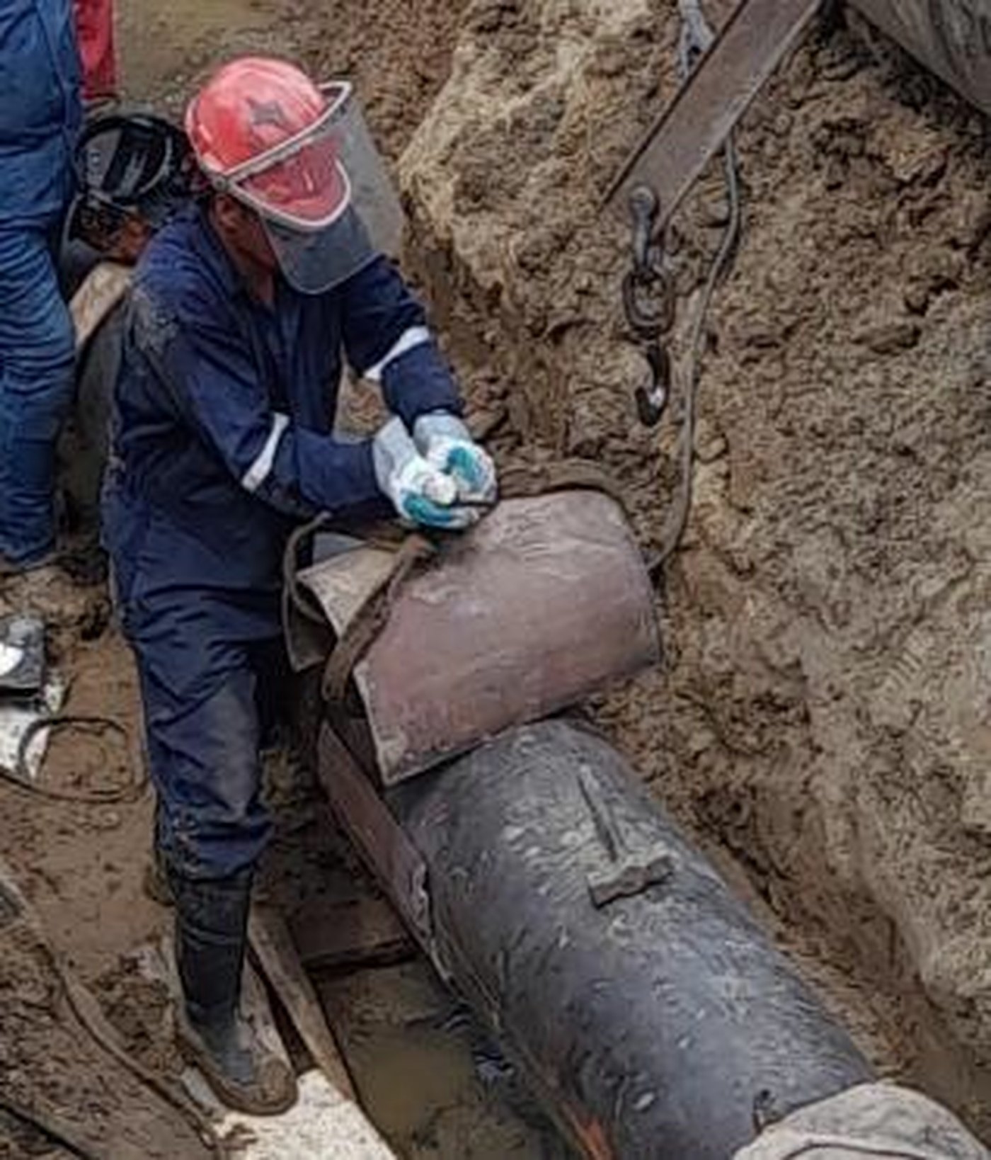 Cuadrilla instalando camisa de acero de refuerzo sobre tubería enterrada